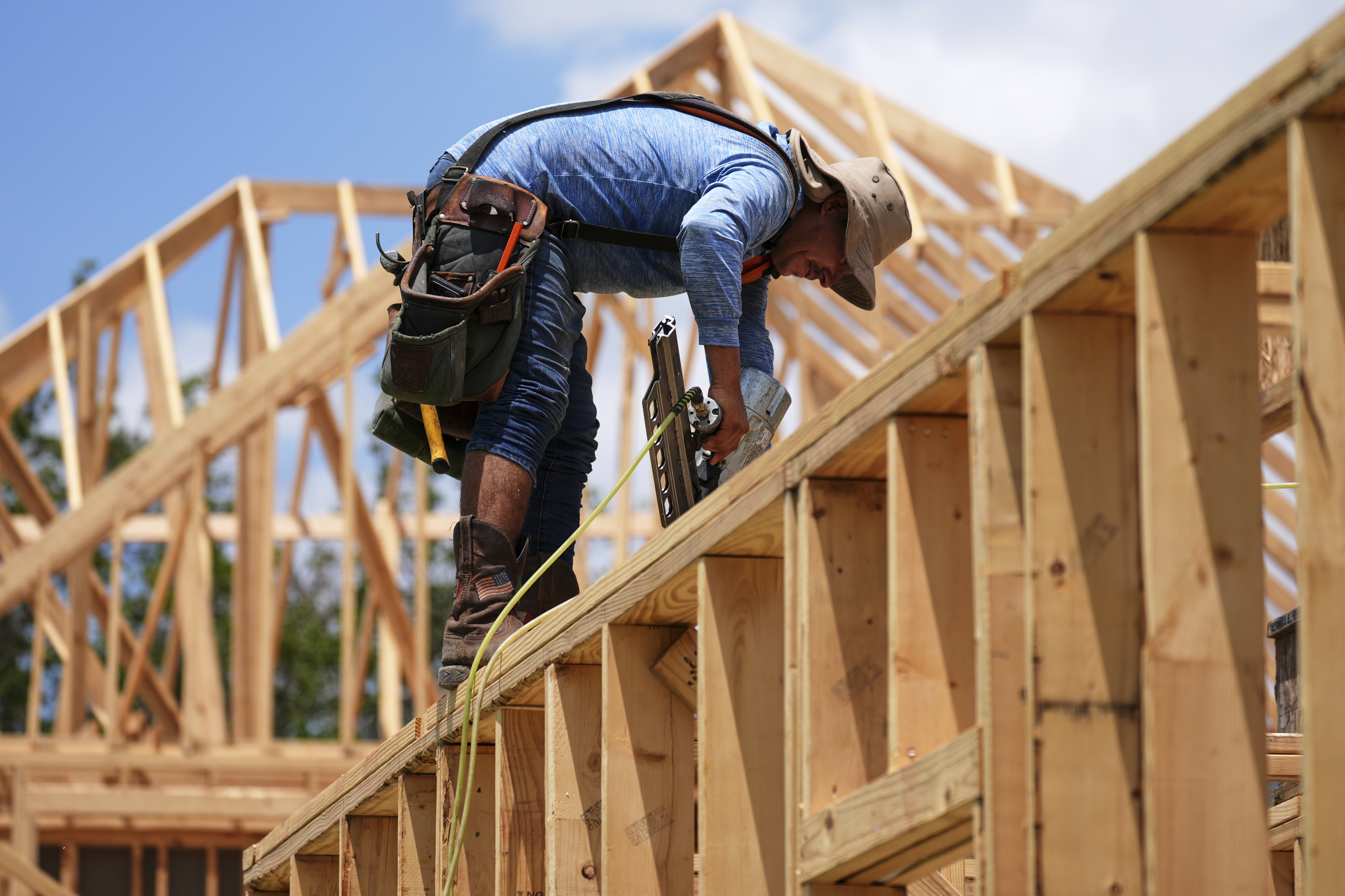 A worker works on the roofing structure of new home under construction, Tuesday, July 15, 2025, in Richardson, Texas.